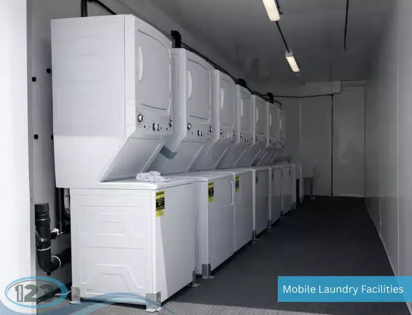 Interior of a mobile laundry trailer with rows of stacked white washers and dryers.